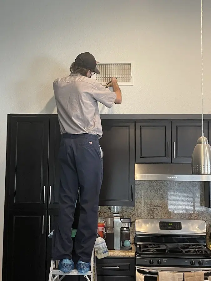 Technician inspecting an air vent during HVAC service in Stuart